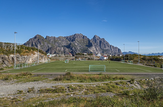 A photo of a football pitch surrounded by mountainous terrain.