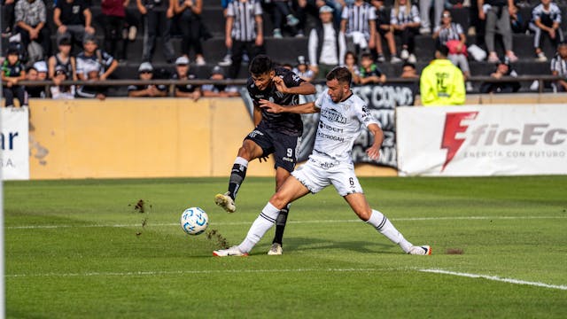 A photo of two football players battling for the ball during a match.