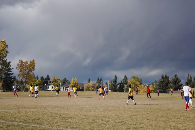 Two teams playing football against each other with storm clouds in the distance.