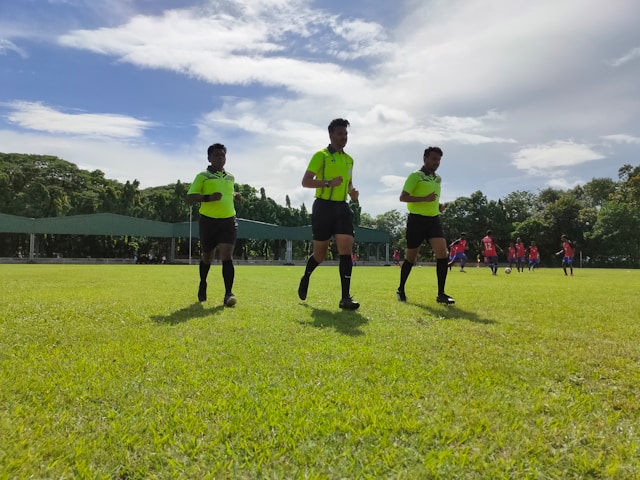 A photo of a referee and two linesmen doing a warm up before a match.