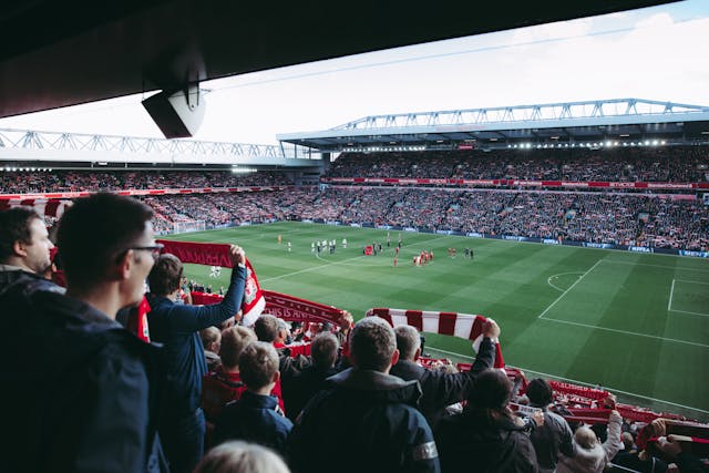 A photo of Liverpool fans raising scarfs  before the start of a game.