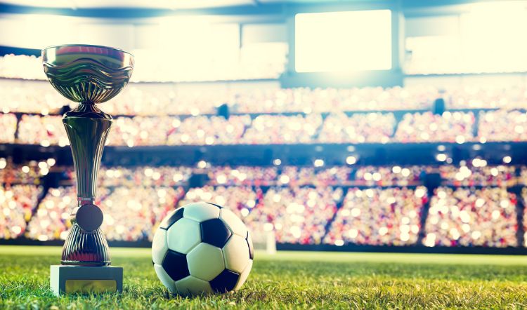 A photo of a trophy and football inside a football stadium.